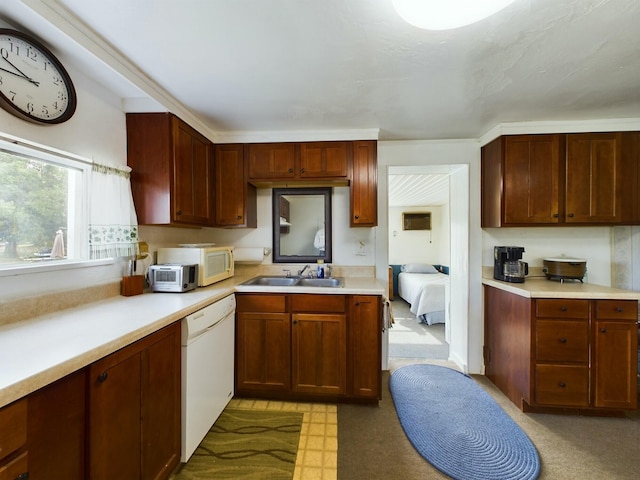 kitchen with light countertops, white dishwasher, and a sink