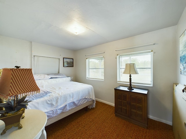 bedroom featuring dark colored carpet and baseboards