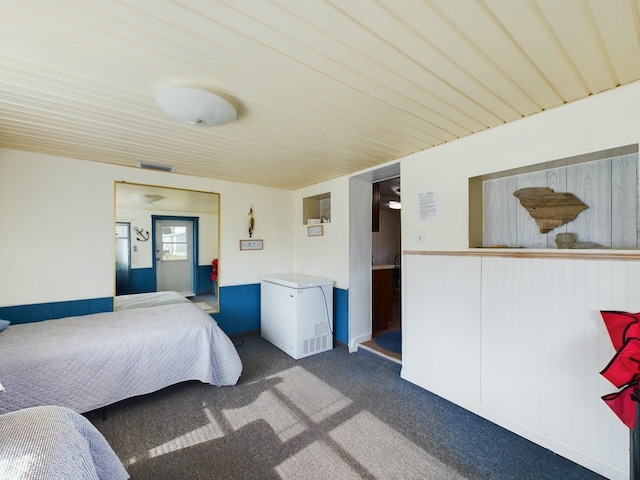 bedroom with carpet floors, refrigerator, and visible vents