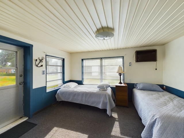 bedroom featuring wainscoting, multiple windows, carpet, and a wall unit AC