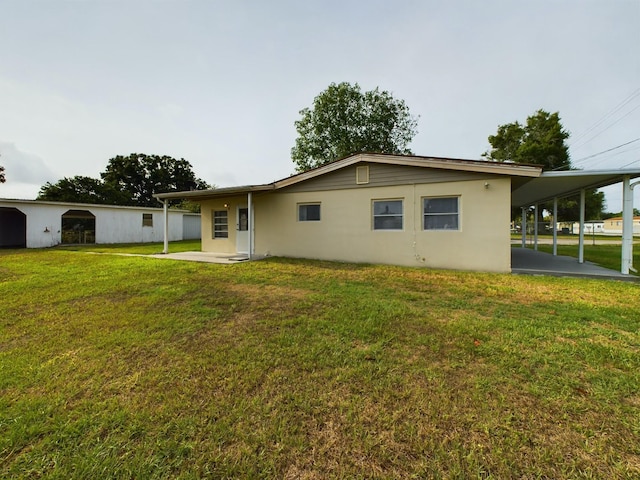 rear view of property featuring a carport and a yard