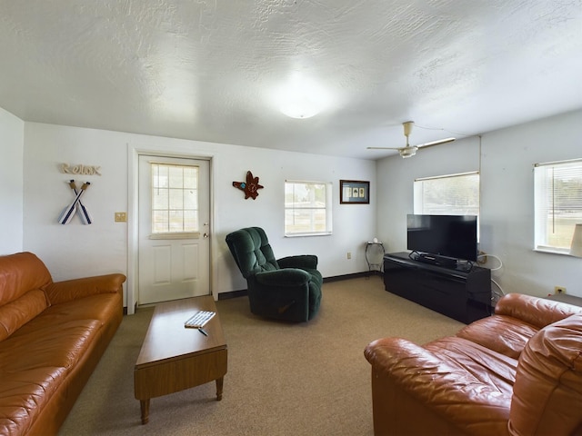 living room featuring light carpet, ceiling fan, a textured ceiling, and baseboards