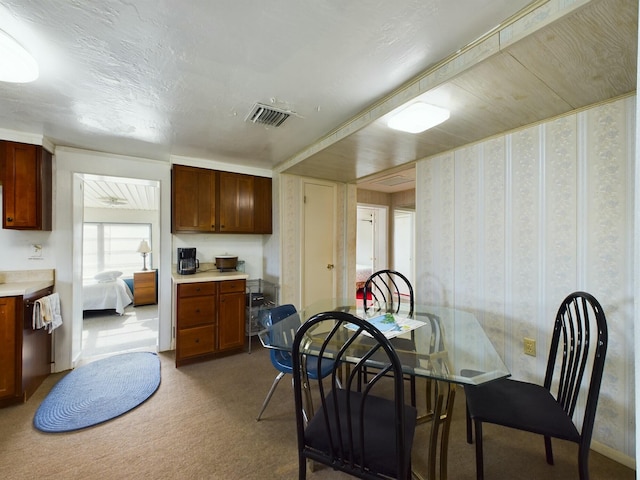 kitchen with light carpet, light countertops, visible vents, and wallpapered walls