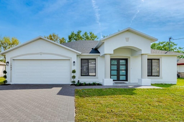 view of front of house featuring decorative driveway, french doors, stucco siding, a front yard, and a garage