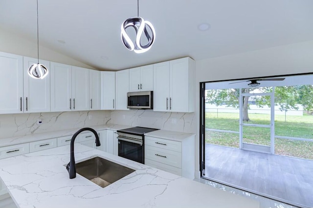 kitchen with stainless steel appliances, a sink, white cabinetry, backsplash, and decorative light fixtures