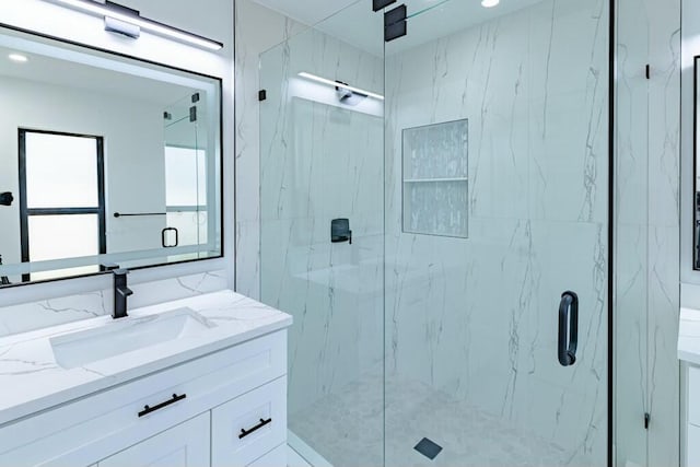 bathroom featuring a marble finish shower and vanity