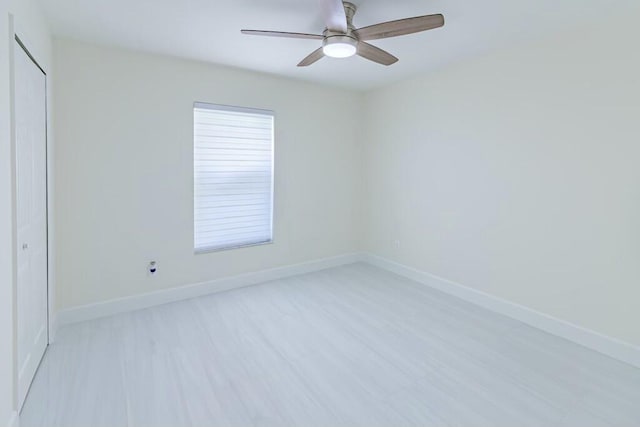 unfurnished room featuring a ceiling fan, light wood-style flooring, and baseboards