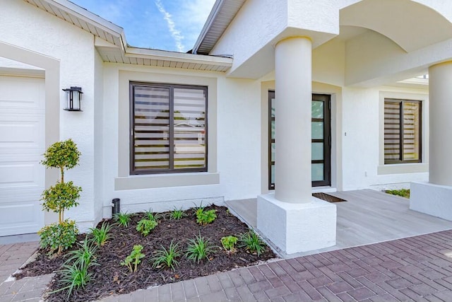 property entrance with a garage and stucco siding