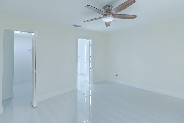 spare room with ceiling fan, visible vents, and baseboards