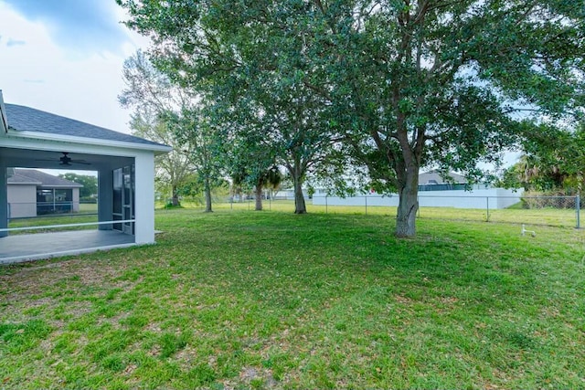 view of yard with ceiling fan and fence