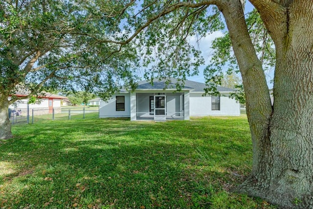 back of property featuring a sunroom, stucco siding, a yard, and fence