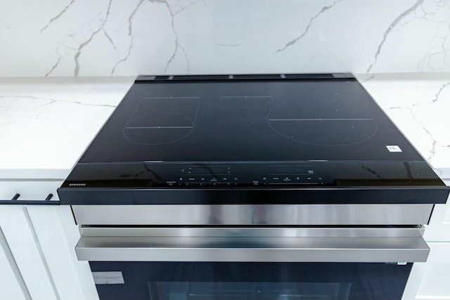 interior details featuring stainless steel electric range oven and light stone counters