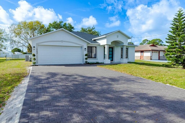 view of front of property with decorative driveway, stucco siding, a front yard, a garage, and cooling unit