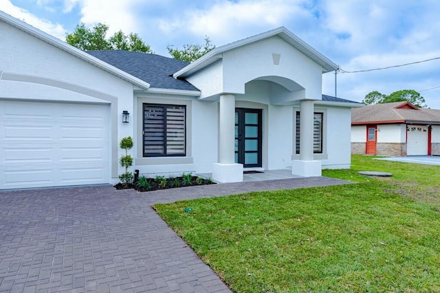 view of front of home with a garage, roof with shingles, a front lawn, and stucco siding