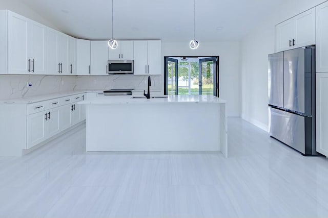 kitchen featuring a center island with sink, decorative backsplash, appliances with stainless steel finishes, white cabinetry, and a sink