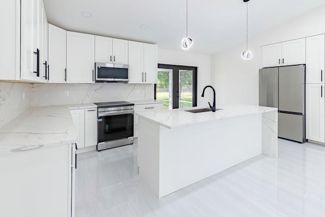 kitchen featuring light stone counters, a sink, white cabinets, appliances with stainless steel finishes, and backsplash