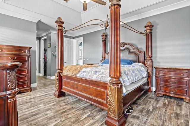 bedroom featuring baseboards, wood finished floors, decorative columns, and crown molding