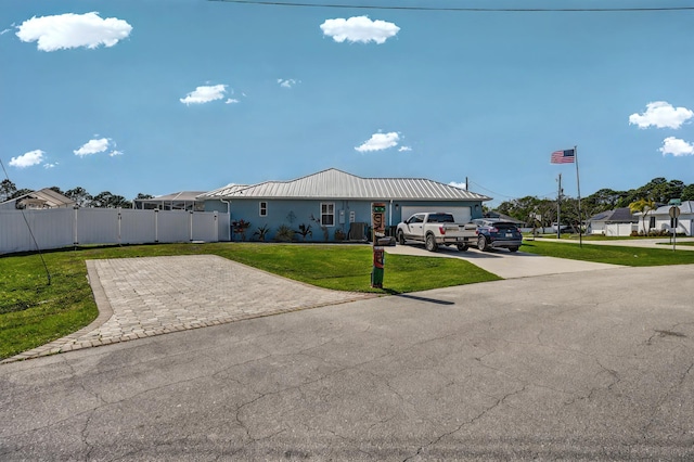 single story home featuring metal roof, fence, a front lawn, and decorative driveway