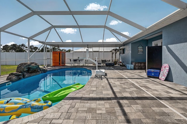 view of pool with a storage shed, a fenced in pool, glass enclosure, fence, and a patio area