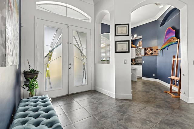 entrance foyer with arched walkways, french doors, and baseboards