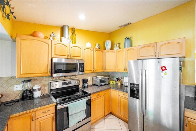 kitchen with light tile patterned floors, stainless steel appliances, visible vents, backsplash, and dark countertops