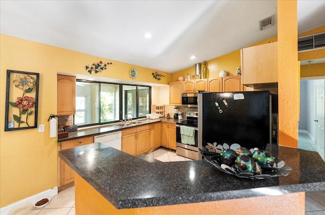 kitchen featuring dark countertops, stainless steel appliances, light brown cabinetry, and a peninsula