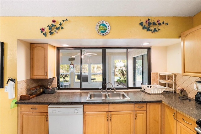 kitchen featuring dark countertops, light brown cabinets, white dishwasher, and a sink