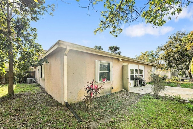 view of property exterior with a patio area, cooling unit, fence, and stucco siding