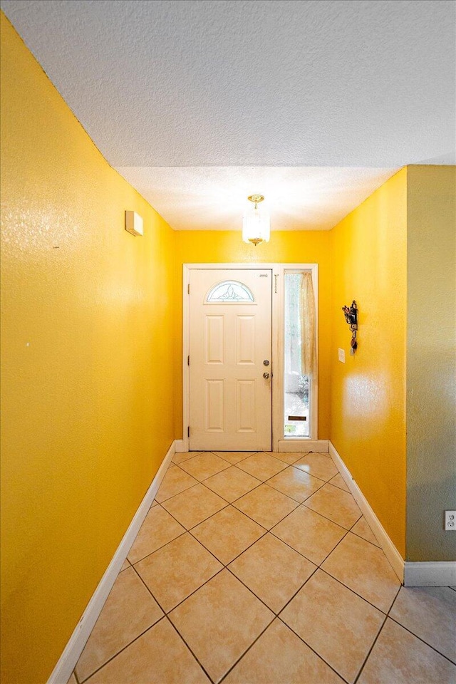 doorway featuring a textured ceiling, baseboards, and light tile patterned floors