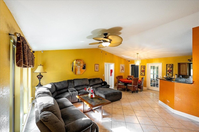 living room with a ceiling fan, vaulted ceiling, baseboards, and light tile patterned floors