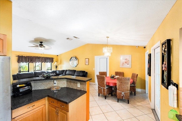 kitchen with visible vents, dark countertops, open floor plan, freestanding refrigerator, and vaulted ceiling