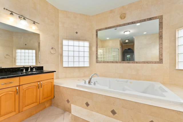 full bathroom with plenty of natural light, a jetted tub, tile patterned floors, and tile walls