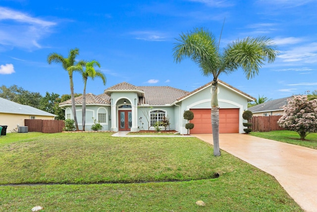 mediterranean / spanish-style home featuring french doors, an attached garage, a front lawn, and fence