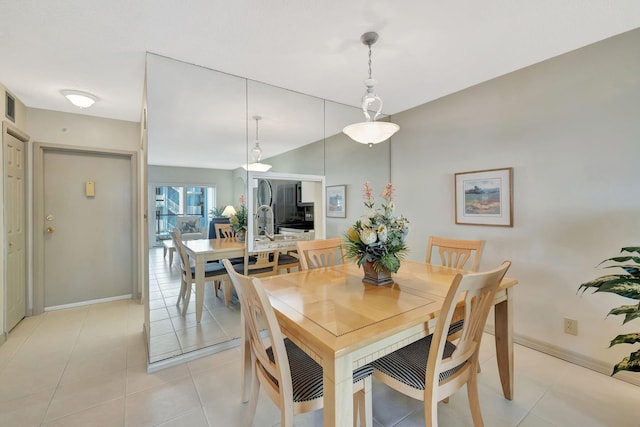 dining room with light tile patterned floors, baseboards, visible vents, and vaulted ceiling