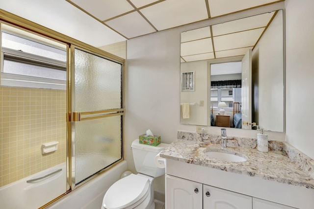 full bathroom featuring toilet, bath / shower combo with glass door, and vanity