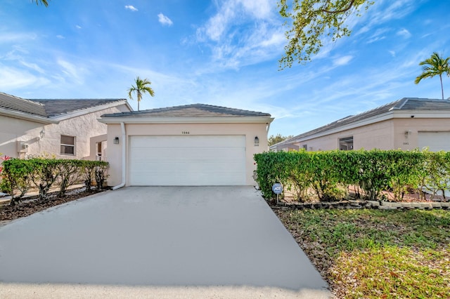 exterior space with concrete driveway, an attached garage, a tiled roof, and stucco siding