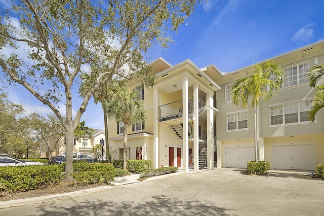 view of building exterior featuring an attached garage, driveway, and stairs