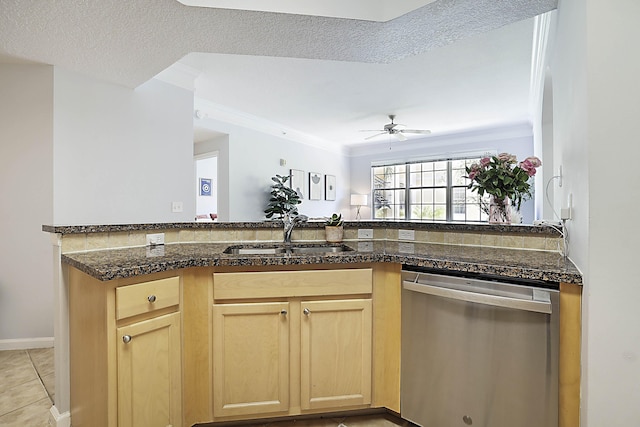 kitchen featuring a peninsula, a sink, dishwasher, light brown cabinetry, and dark stone countertops