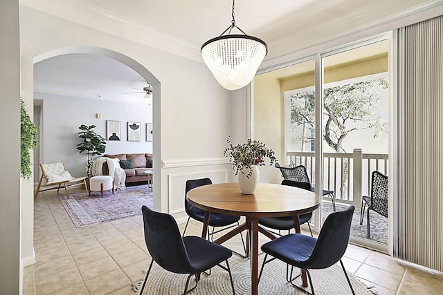 dining space featuring light tile patterned flooring, ceiling fan with notable chandelier, arched walkways, and ornamental molding