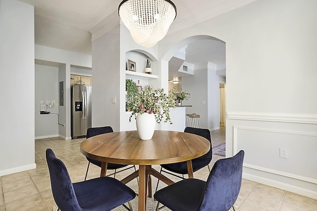 dining room featuring a chandelier, light tile patterned floors, crown molding, and built in features