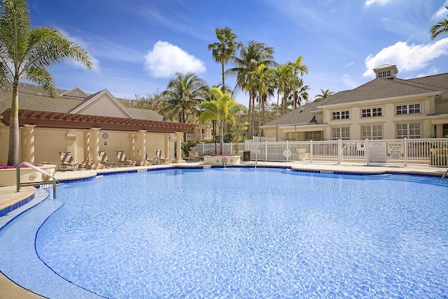 community pool with a patio area and fence