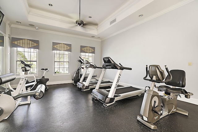 exercise room with baseboards, visible vents, a raised ceiling, and crown molding