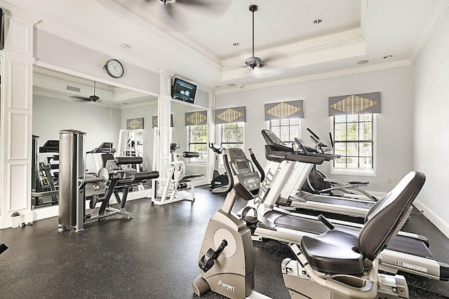 exercise room with a tray ceiling, visible vents, a ceiling fan, ornamental molding, and baseboards