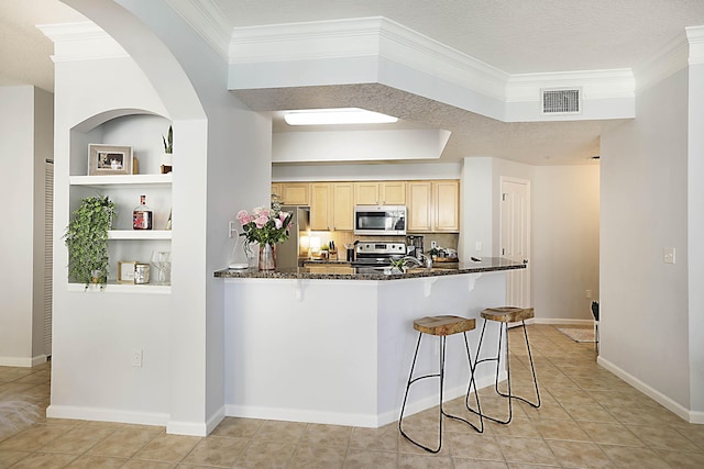 kitchen featuring light tile patterned floors, stainless steel appliances, visible vents, light brown cabinetry, and dark stone countertops