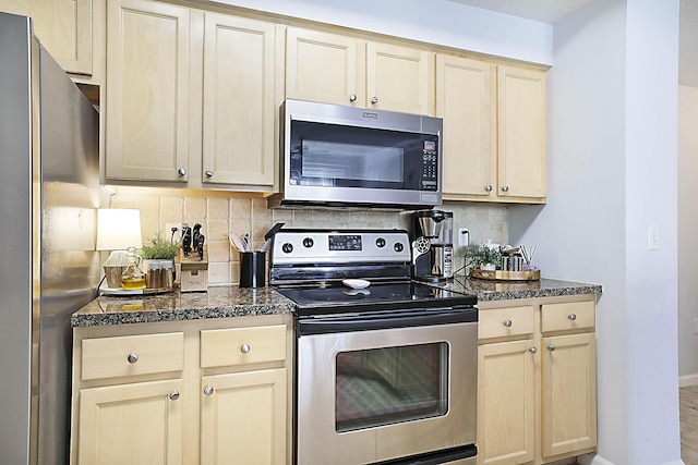 kitchen with stainless steel appliances, baseboards, decorative backsplash, dark stone counters, and light brown cabinetry