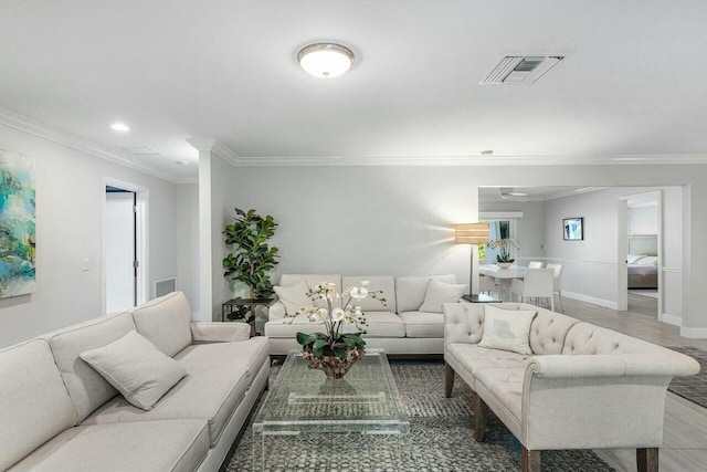 living area with ornamental molding, visible vents, baseboards, and wood finished floors