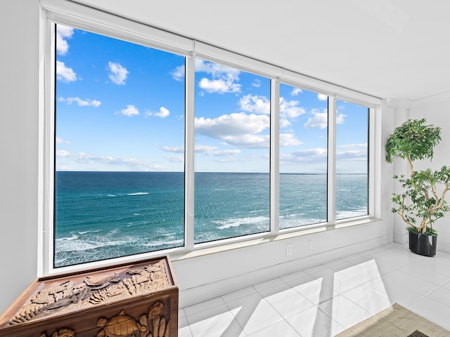 sunroom / solarium featuring a water view and a beach view