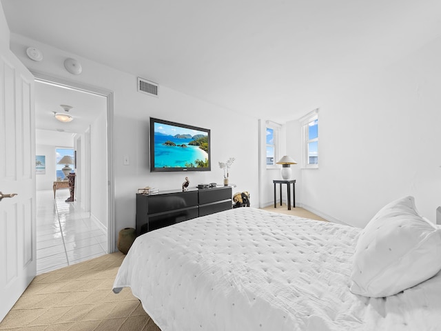 bedroom with light carpet, baseboards, visible vents, and light tile patterned flooring