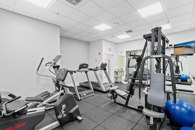 gym with a paneled ceiling, baseboards, and visible vents