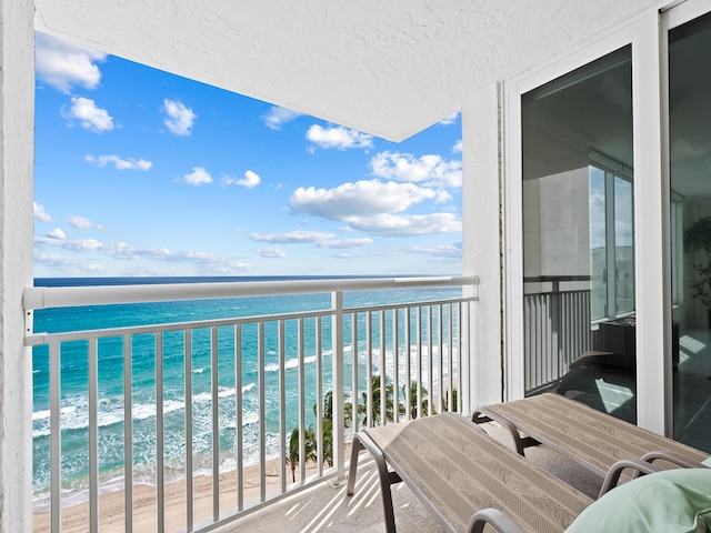 balcony featuring a water view and a view of the beach